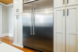 a stainless steel refrigerator surrounded with wooden cabinets.