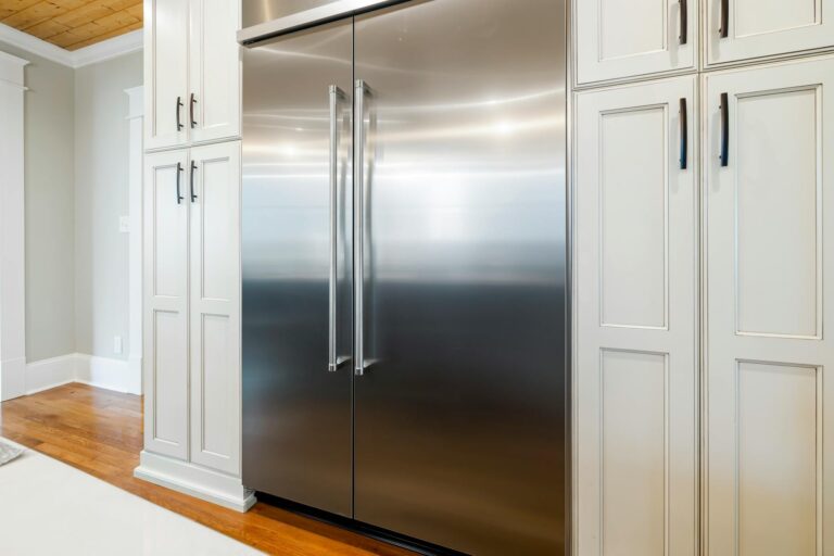 a stainless steel refrigerator surrounded with wooden cabinets.